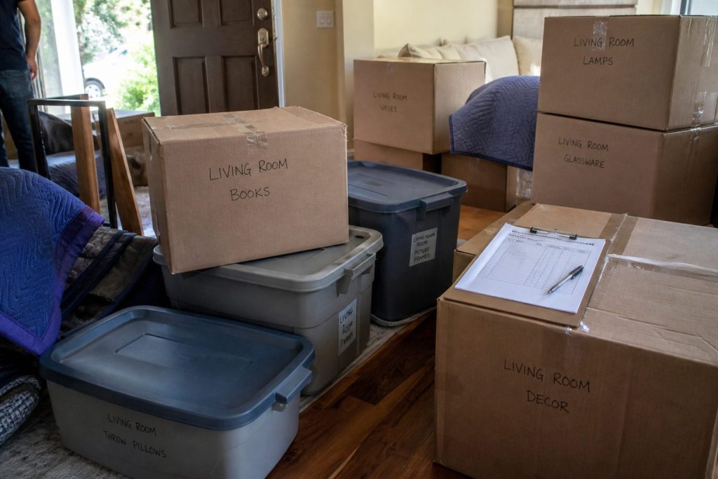 Labeled contents pack-out boxes and bins stacked in a living room for inventory