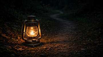 An oil lantern glowing in the dark, its light revealing a path forward