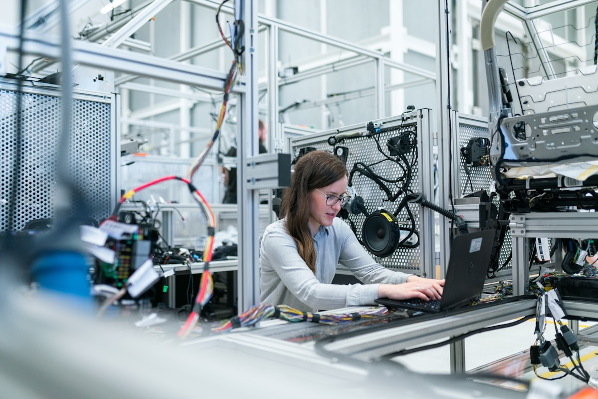 Engineer reviewing a 3D-printed part next to a laptop in a workshop