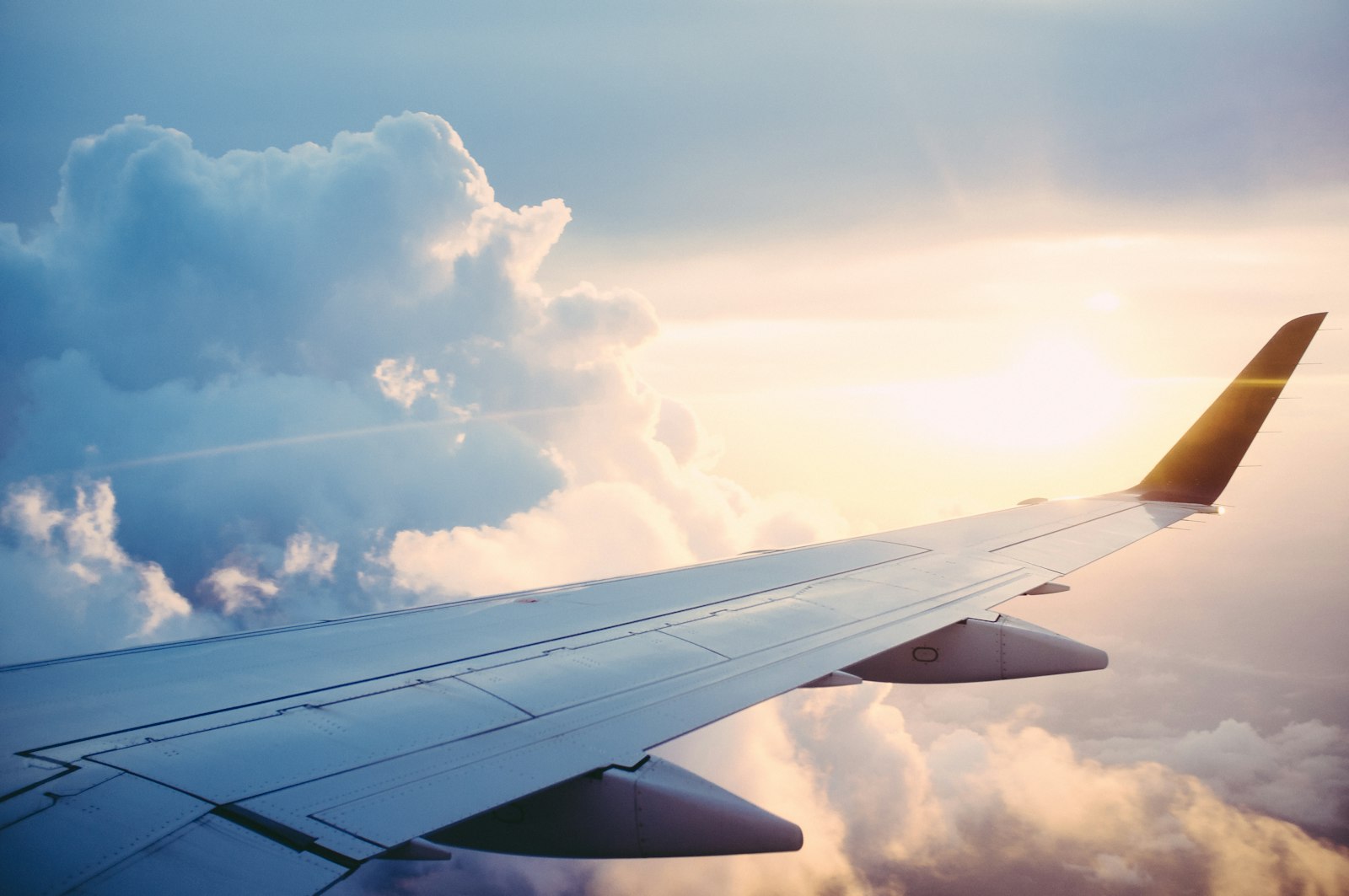 Airplane wing above clouds, photographed from a passenger window