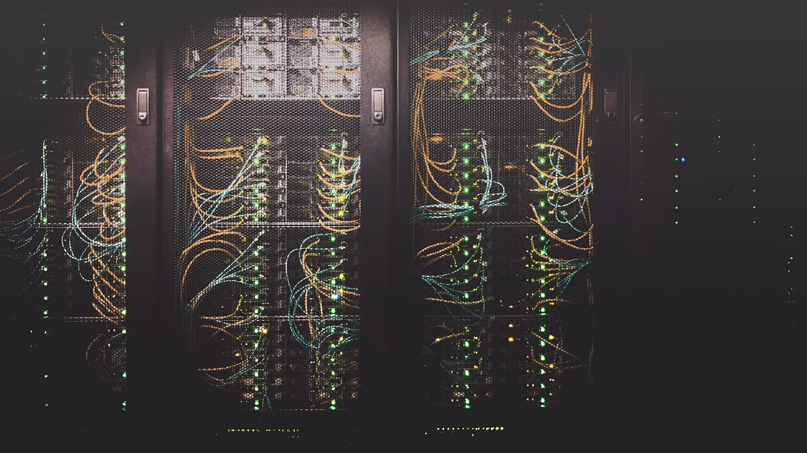 Rows of server racks in a dim data-center aisle with blue status lights